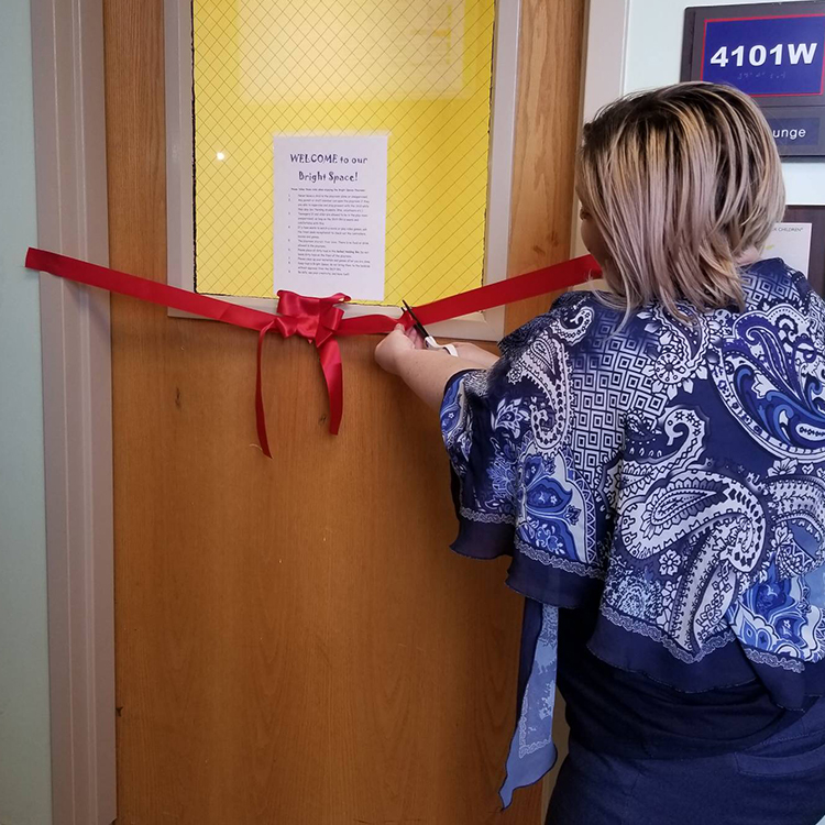 A volunteer cutting a ribon for a new brightspace opening