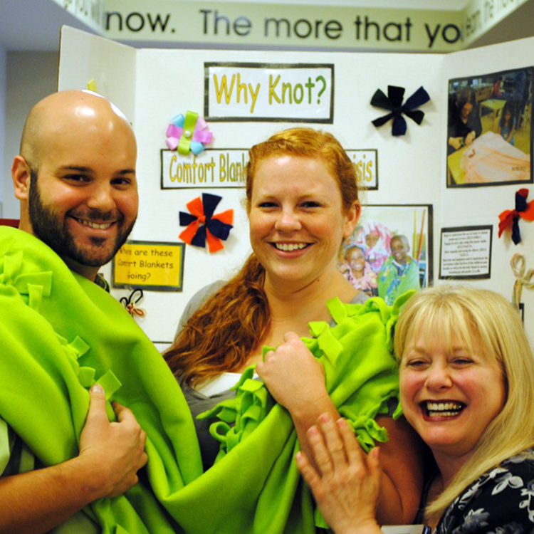 3 volunteers smile as they help build a brightspace